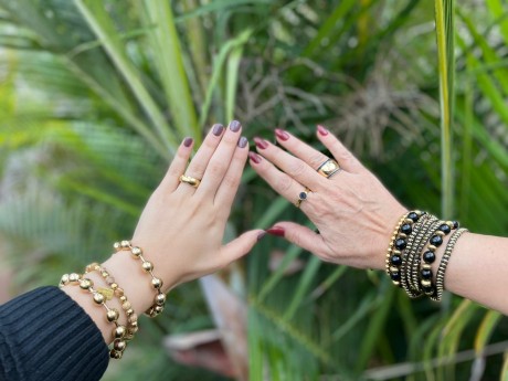 על היד משמאל צמיד כדורים בגוון זהב בהיר בשילוב צמיד חרוזים מאיה אהרוני תכשיטים 